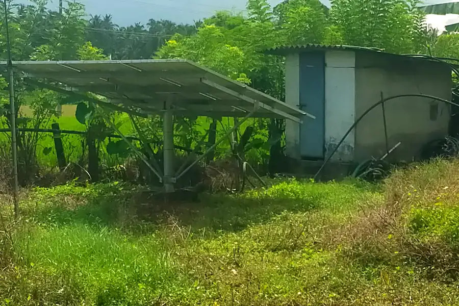 Solar tracker structure with pump house near green paddy fields