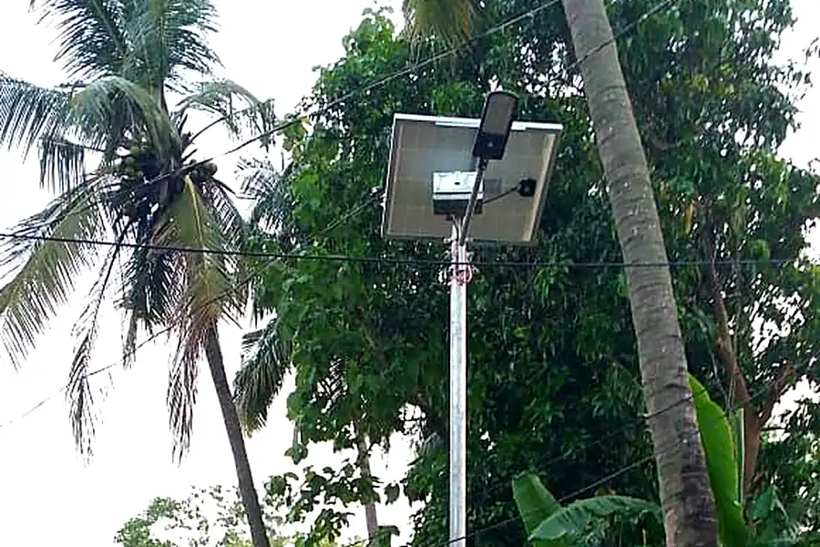 Installation team erecting a solar street light pole in a village