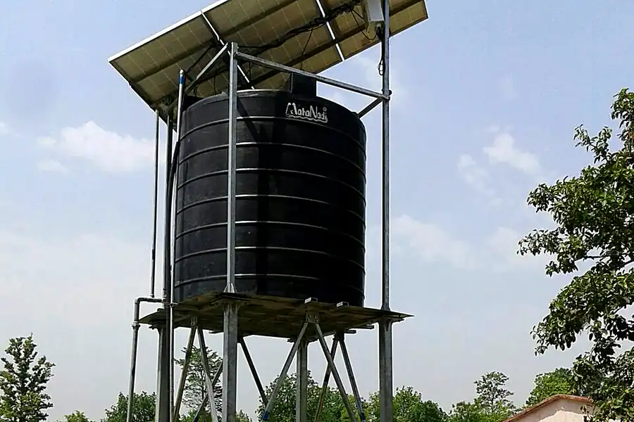 Solar panel topped water tank tower with villager collecting water