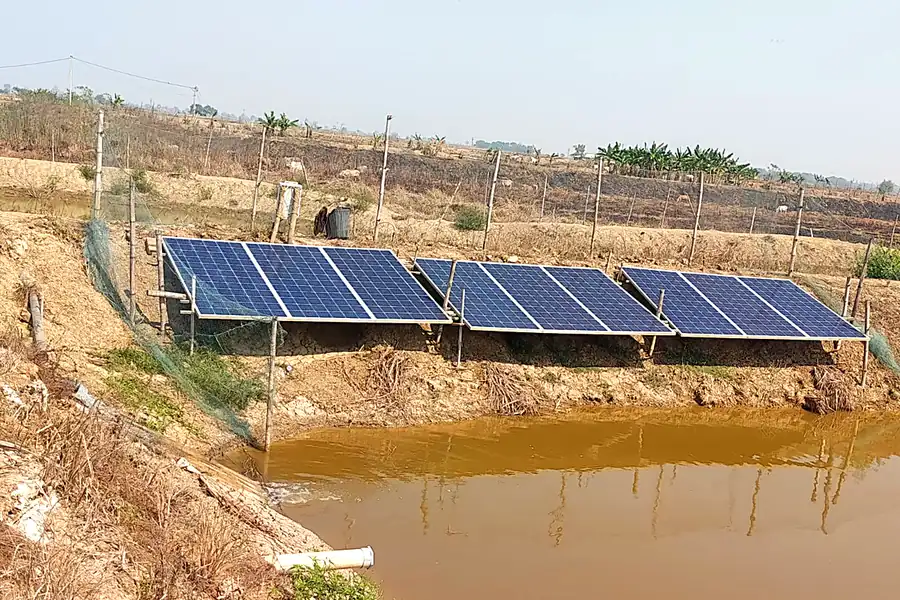 Three solar panel arrays installed on a farm pond bund