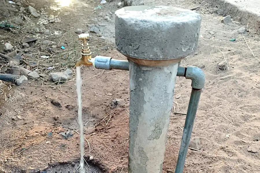 Village stand post with treated water flowing from tap