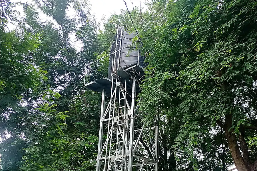 Overhead tank tower installation among village trees